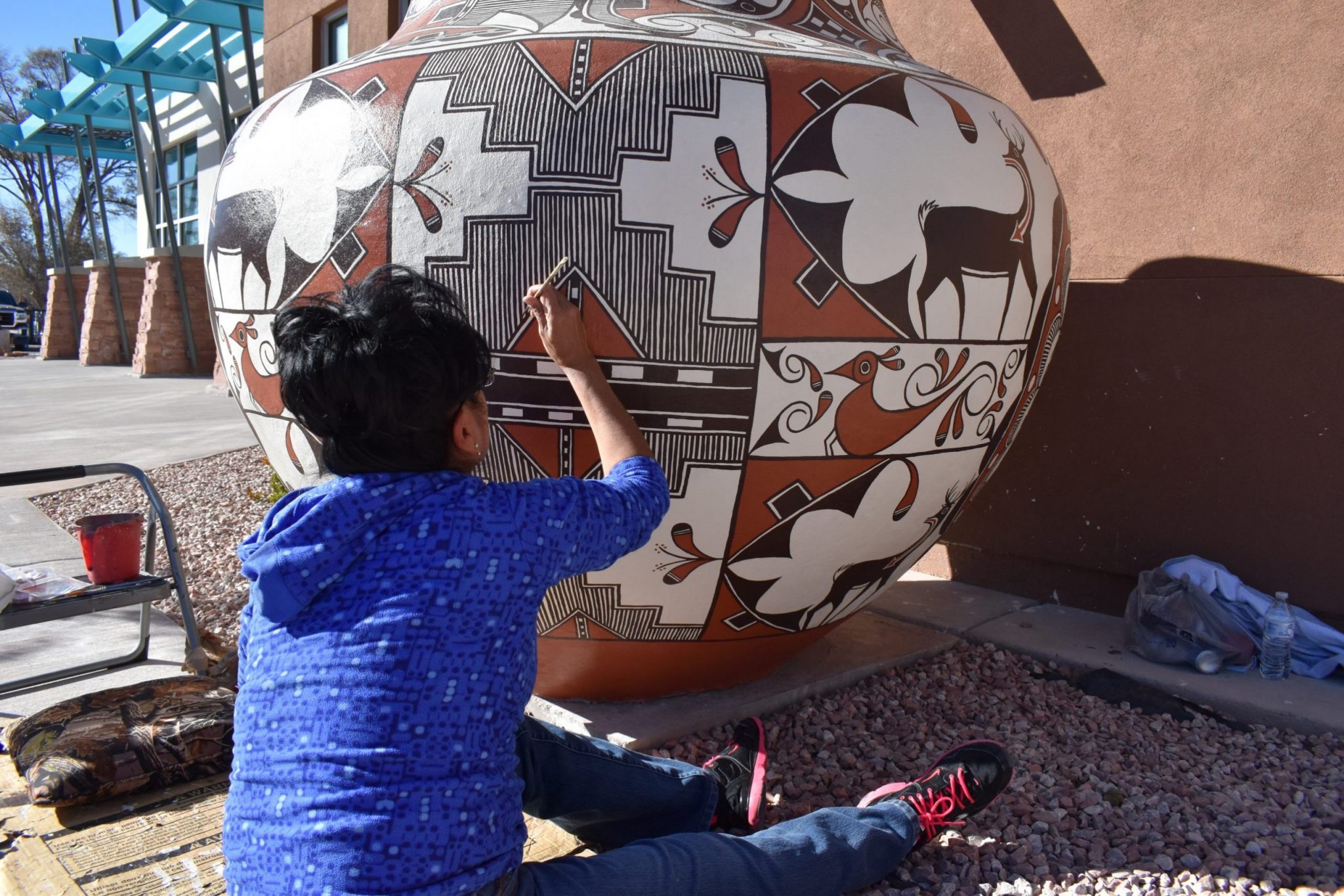 Zuni artist Noreen Simplicio, finishing her large Zuni Olla Pot that serves as water collection of the youth center building. Photo courtesy of the Zuni Youth Enrichment Project Source: https://shelterforce.org/2021/09/23/a-park-that-affirms-a-cultures-rich-traditions/#0